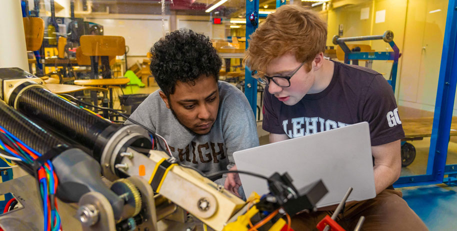 Two students looking into a robotics project together