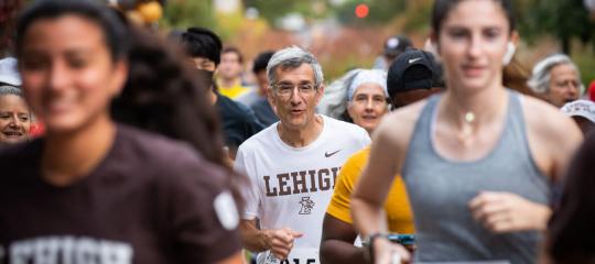 President Helble running, surrounded by students and other runners