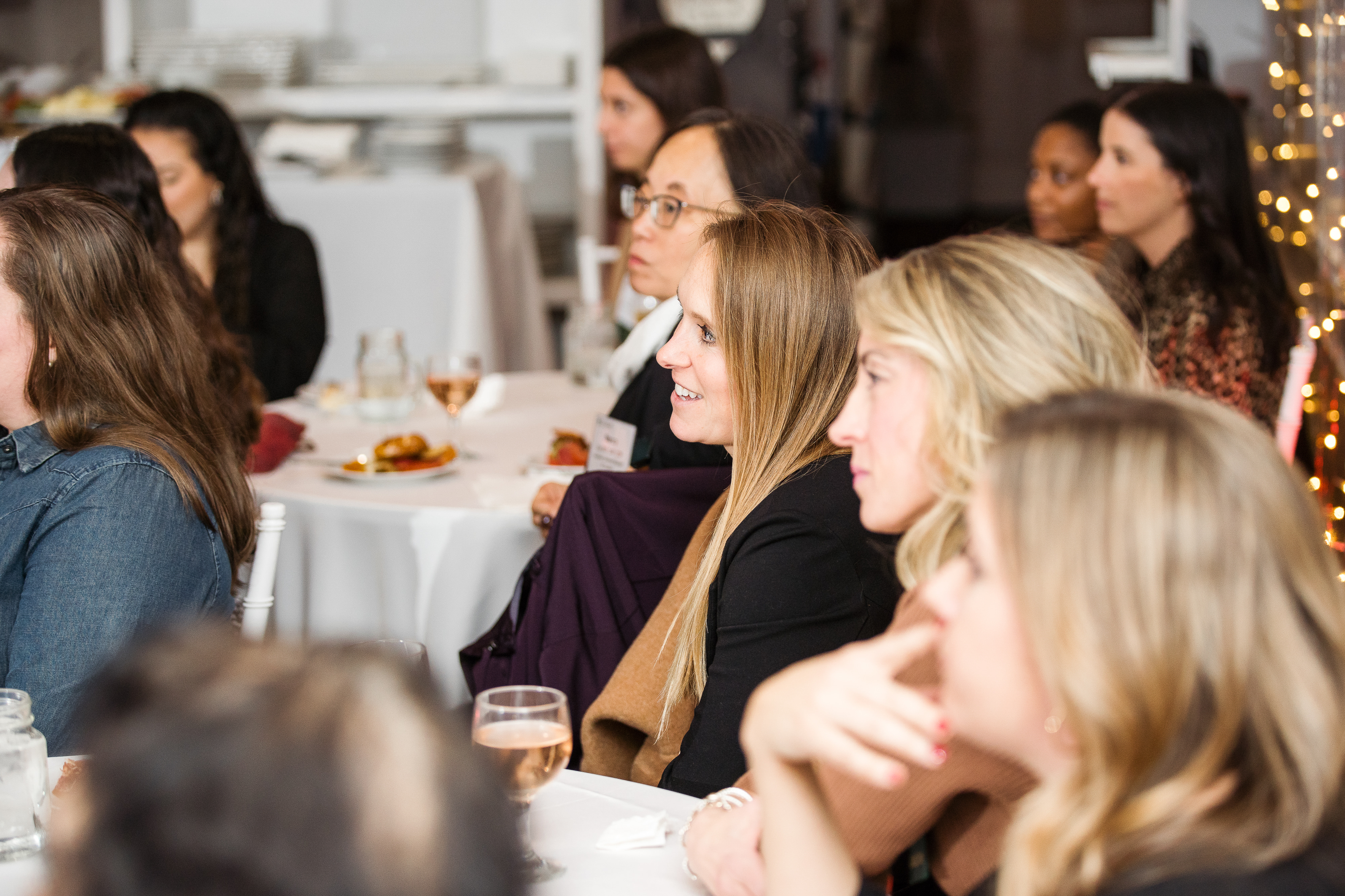 Women sitting around round tables with white tablecloths