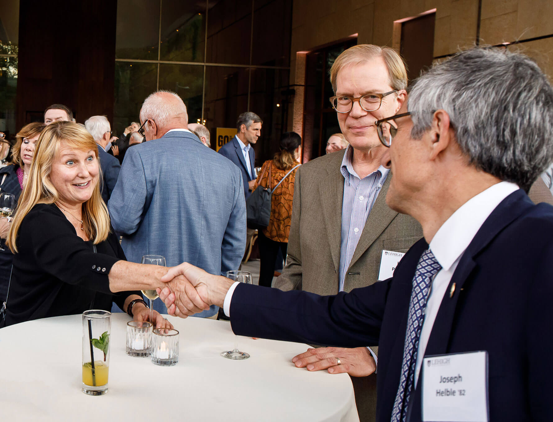 President Joseph J. Helble shaking a woman's hand over a white tablecloth