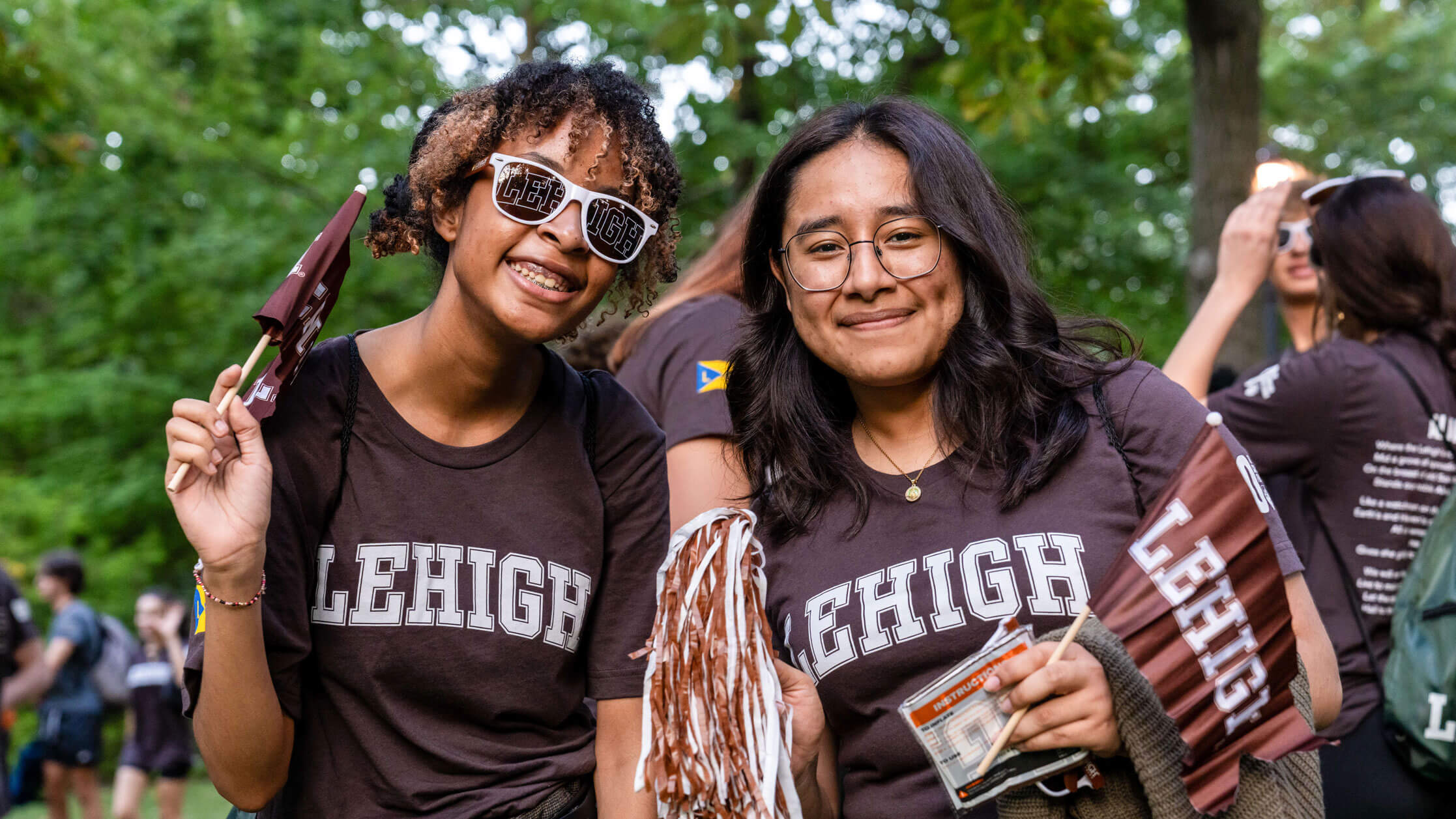 Two female students wearing brown Lehigh t-shirts while waving little Lehigh flags 