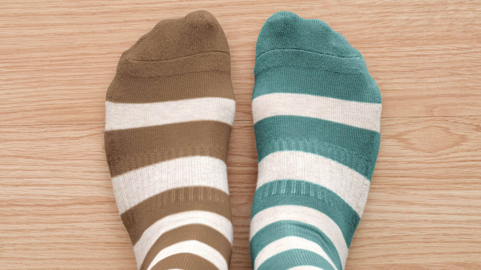 Two feet wearing brown and green mismatched, striped socks