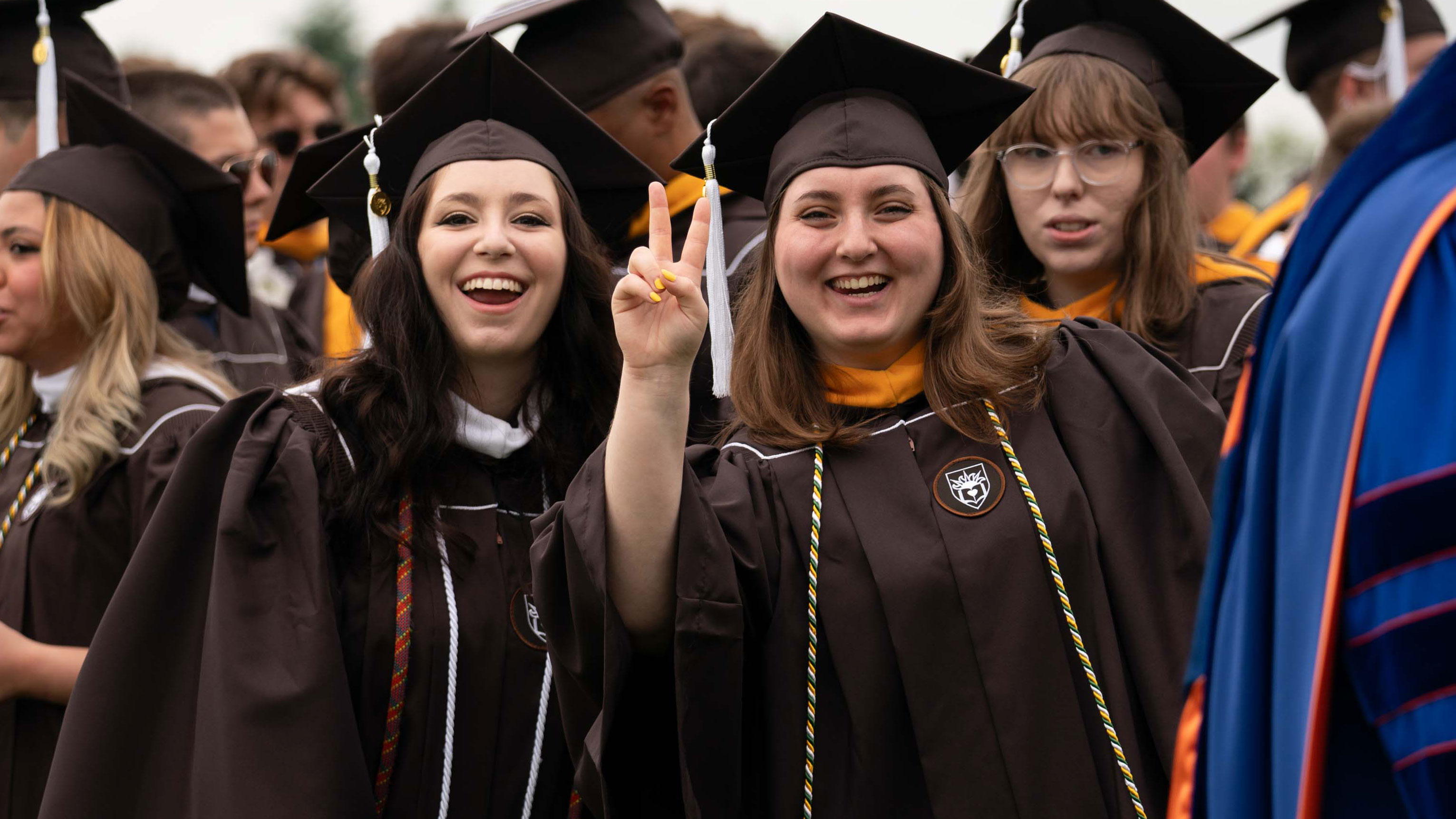 Two female graduates smiling and dressed in their commencement regalia