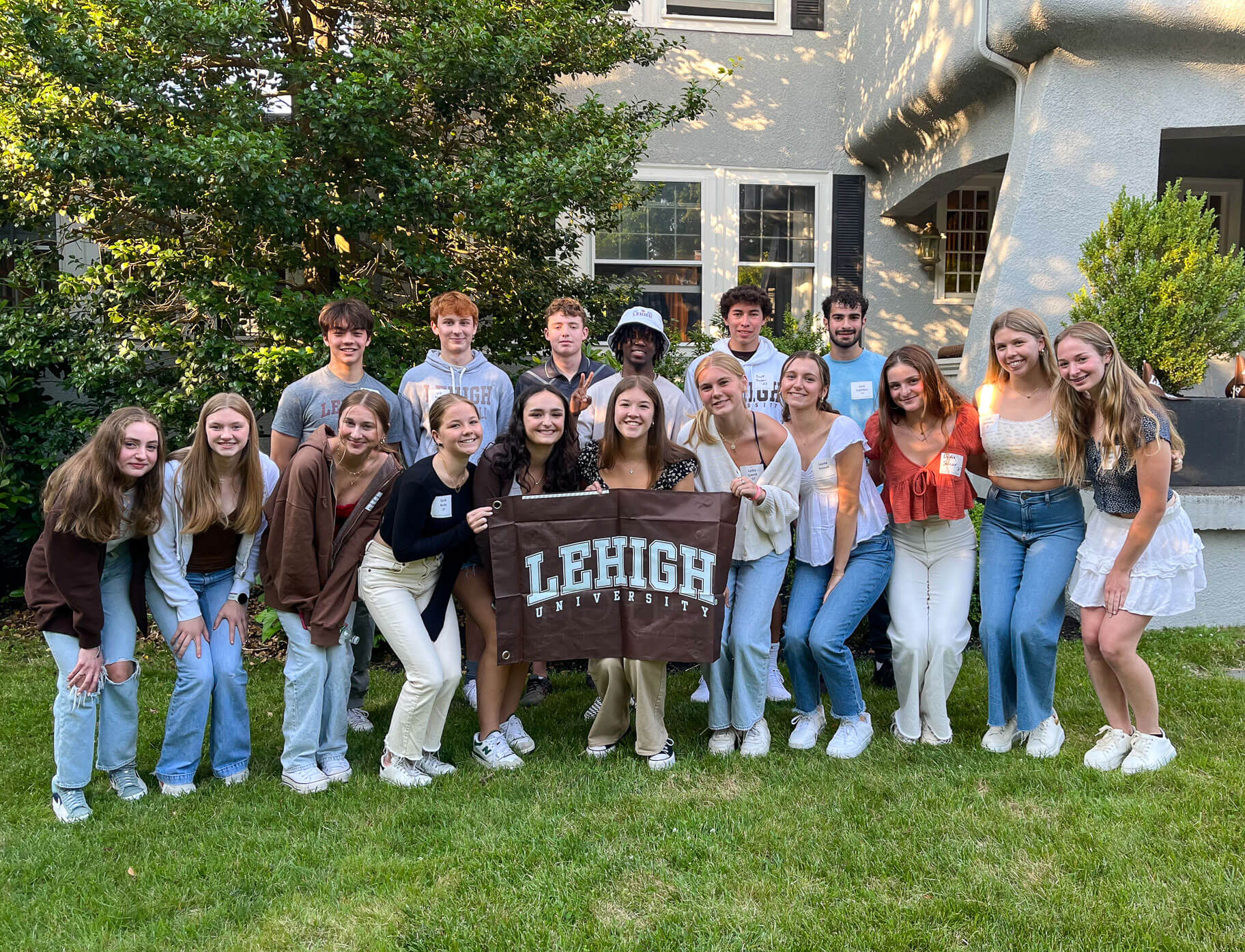 A group of Lehigh students hold a brown Lehigh flag and gather for a photo during an outdoor Sendoff event.