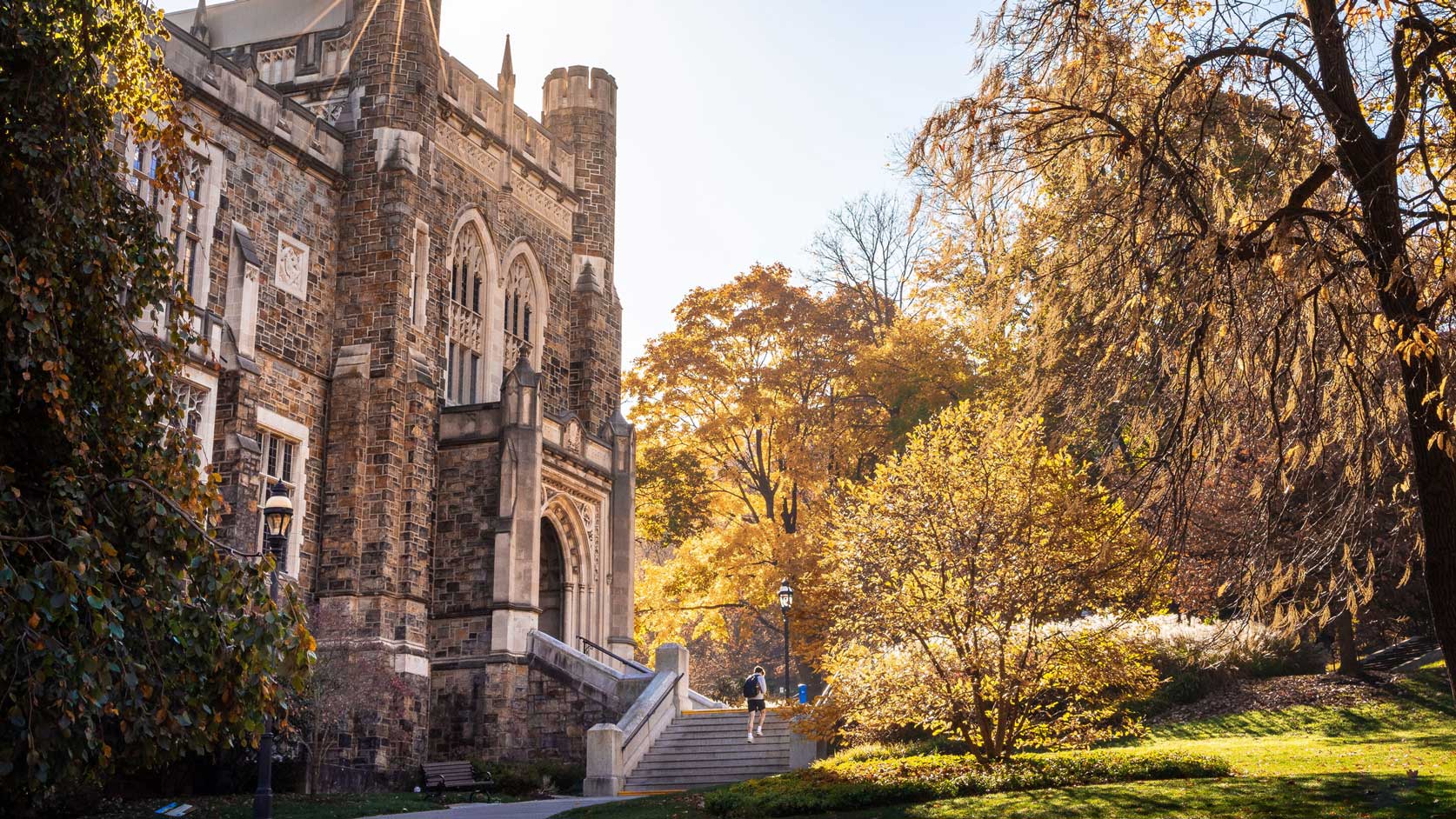 The sun shining behind Linderman Library in the fall.