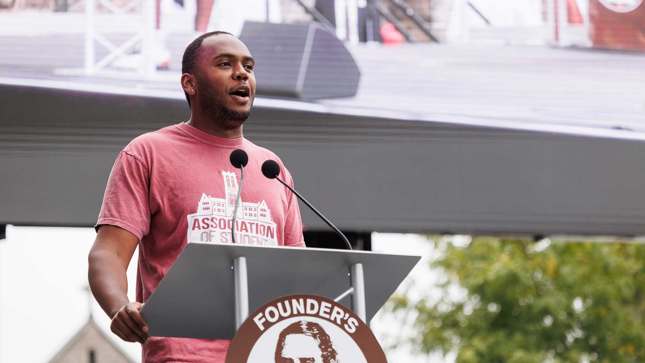 Jermaine Marshall Standing behind a podium and speaking during Family and Founder's Weekend