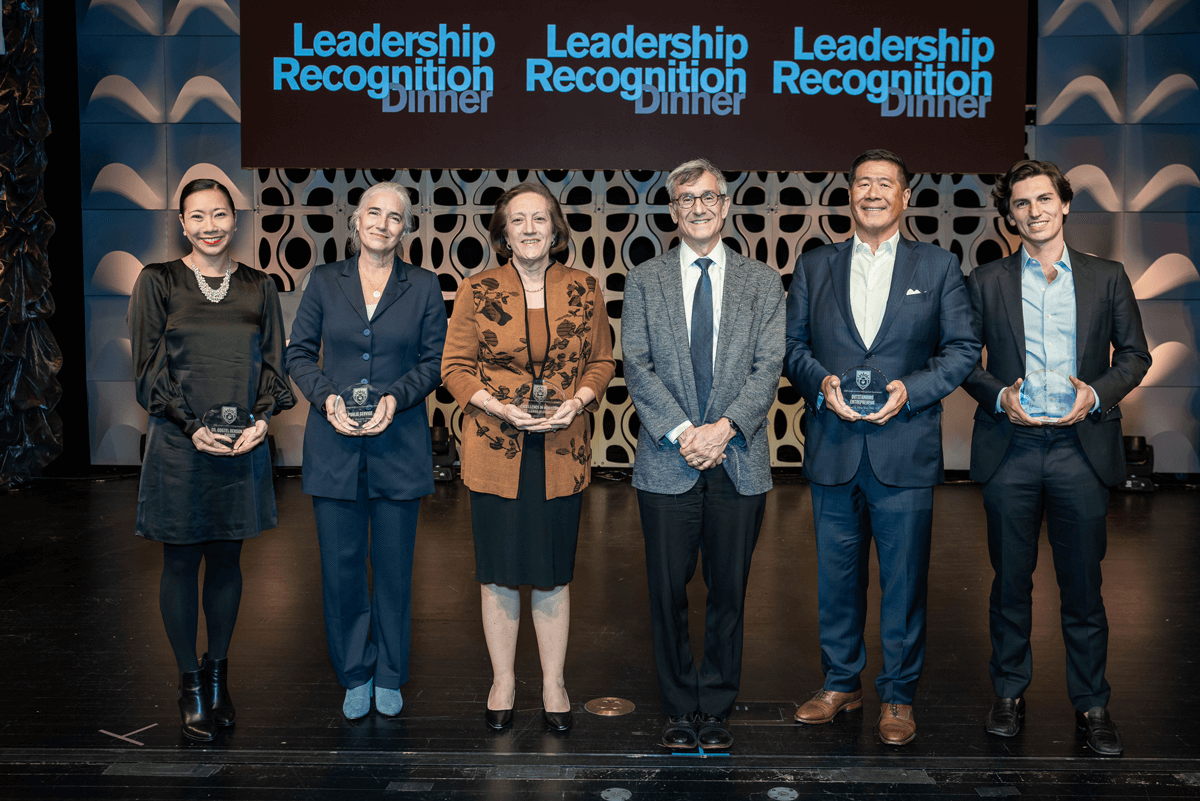 Distinguished Alumni Award recipients stand on stage with their award in hand for a photo with Lehigh President Joseph J. Helble