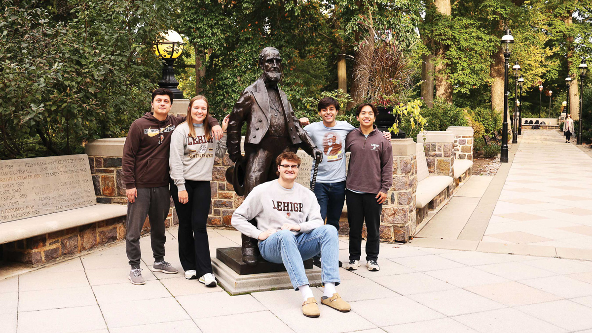 Five students gather around the statue of founder, Asa Packer.