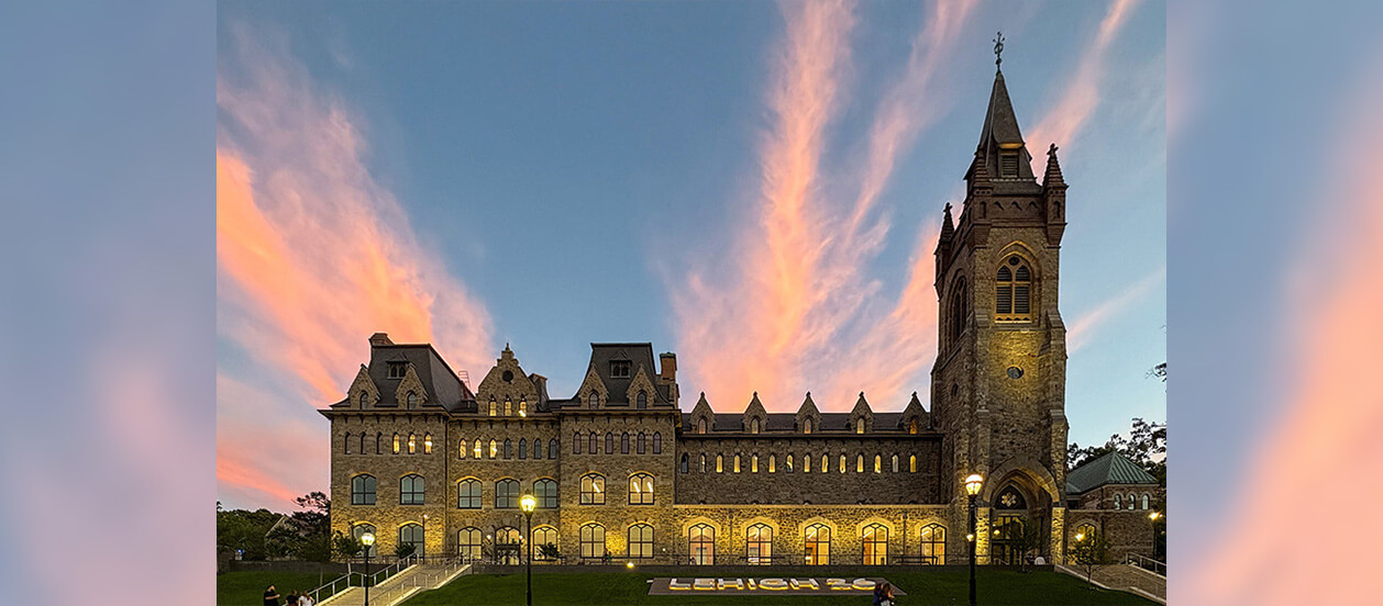 A view of the Clayton UC from the front lawn at twilight with a pink and blue sky sunsetting behind it.