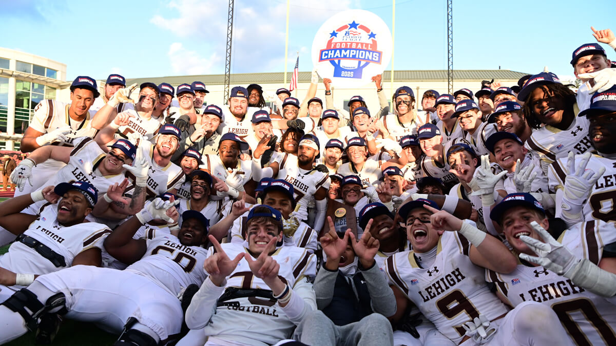 Lehigh football players in white uniforms poise for a group photo and hold a "Patriot League Champions" sign