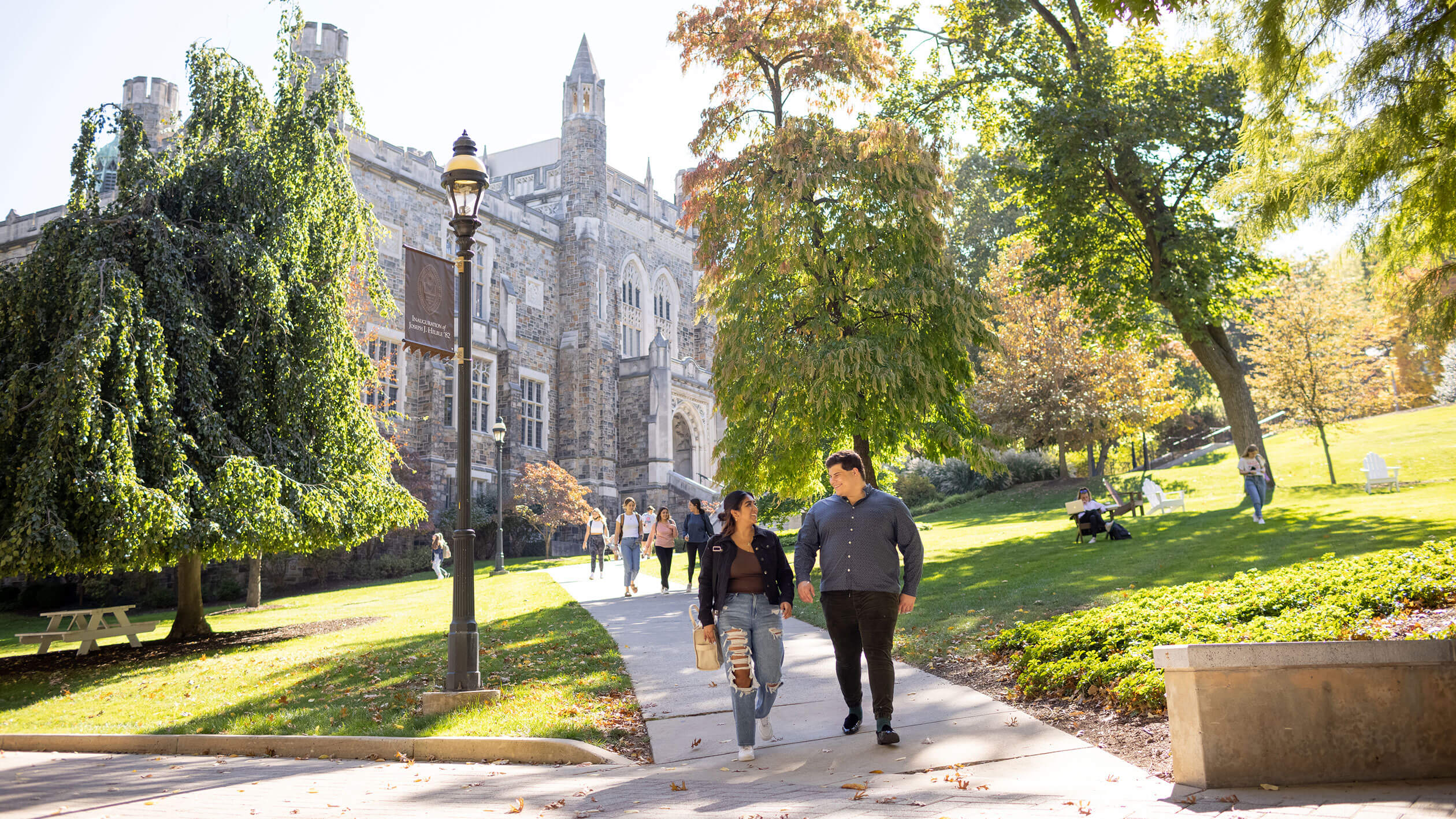 Two people smiling and walking down a concrete pathway on campus