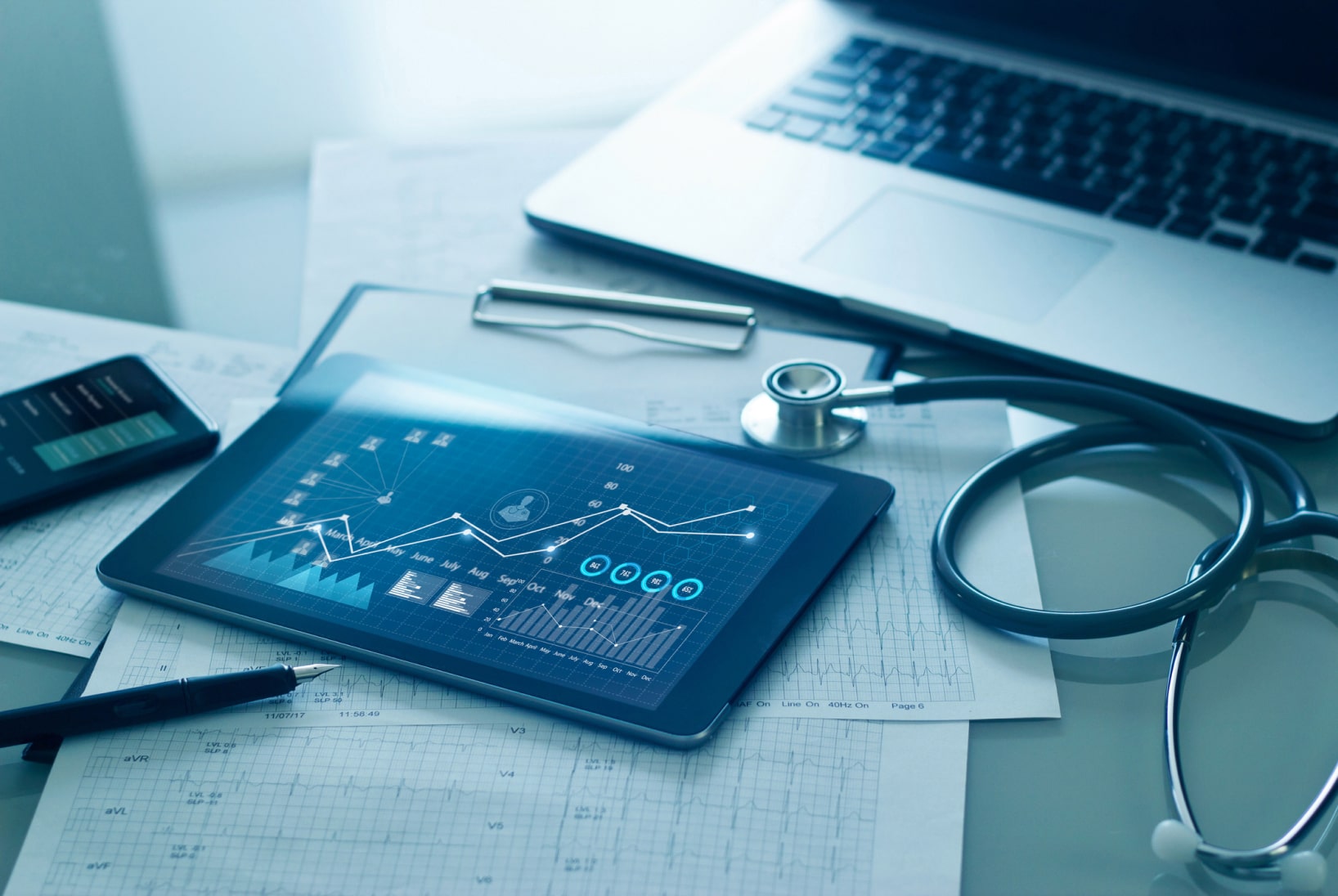A stethoscope and tablet laid on a table while portraying a variety of graphs.