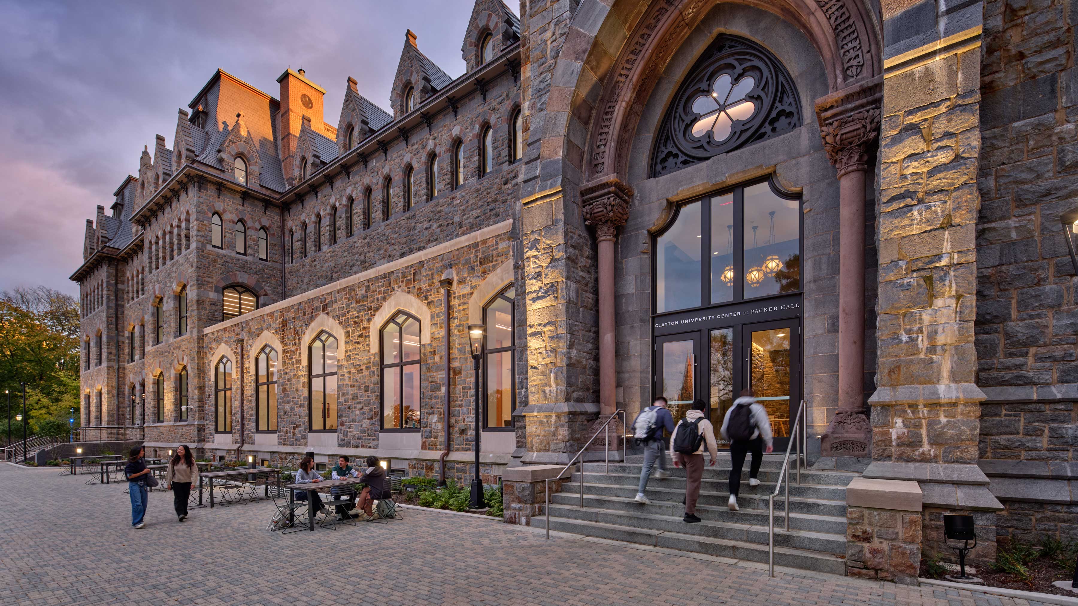 Students sitting at tables and walking around the entrance to the Clayton UC.