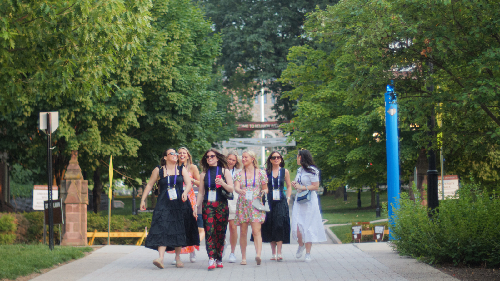 A group of alumnae walk and laugh along a tree-lined campus path during a Lehigh University reunion event.