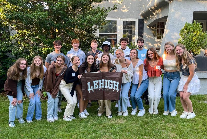 Incoming students posing with a brown Lehigh University flag at a Boston Student Sendoff