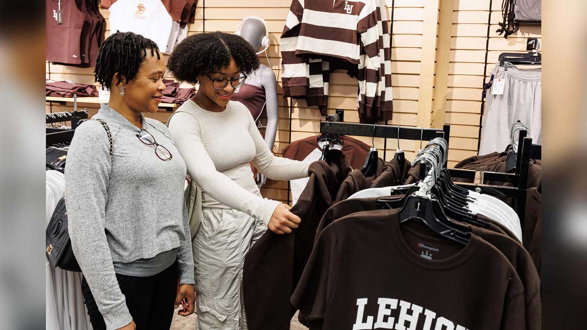 Two women admiring a brown Lehigh hoodie while standing together in the Lehigh Store