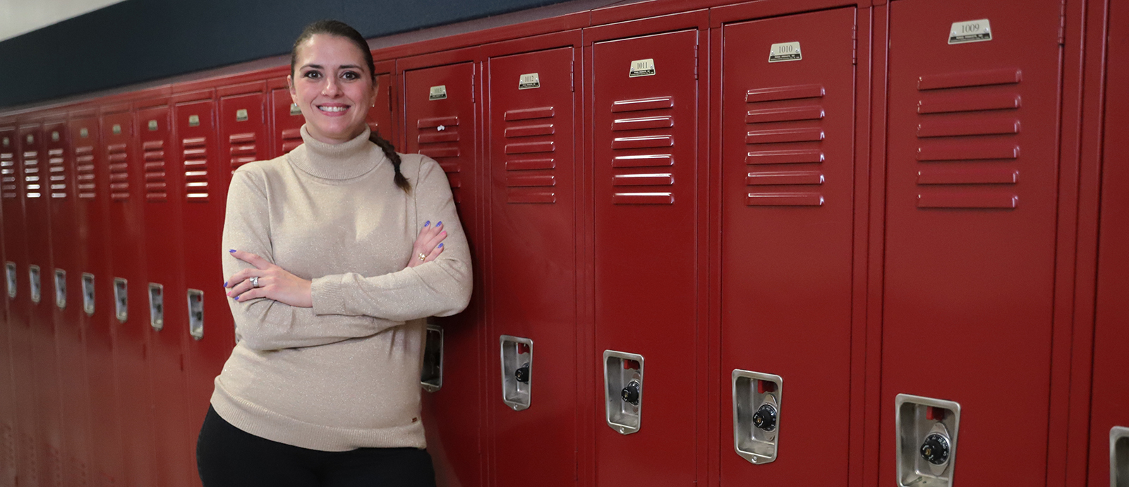 Toni leans on a set of lockers in the hallway