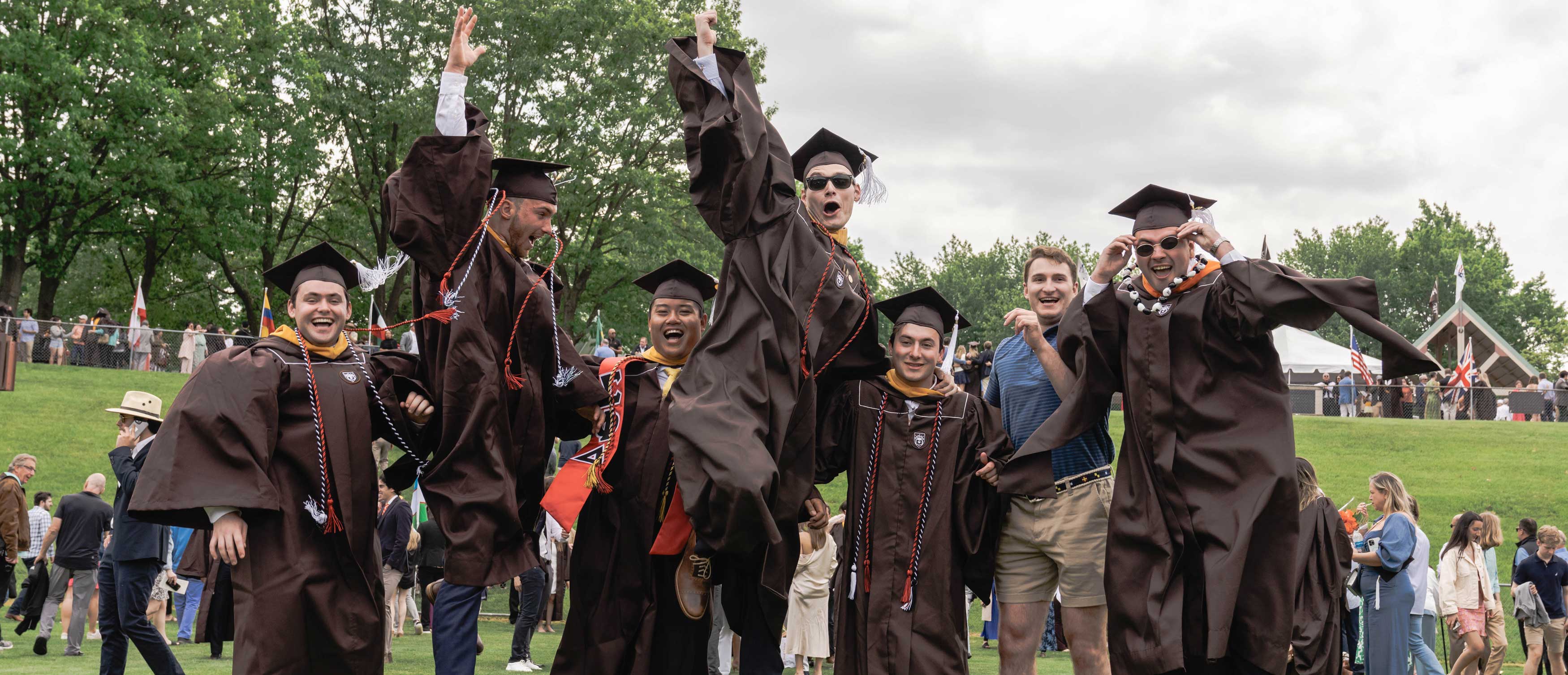 Students wearing their commencement regalia and jumping for literal joy.