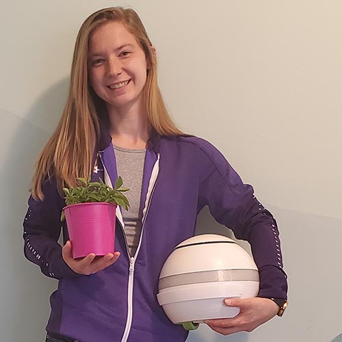 Deanna Kocher smiling and holding a potted plant.