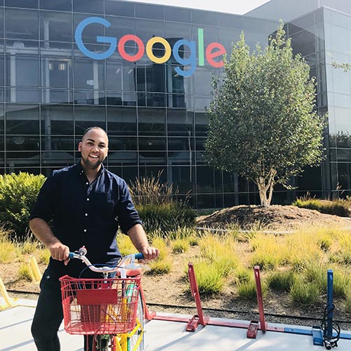 Jonathan Jean-Pierre posing with a bicycle outside of Google offices.