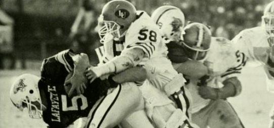 Vintage photograph of a Lafayette footbal player trying to maintain control of the ball.