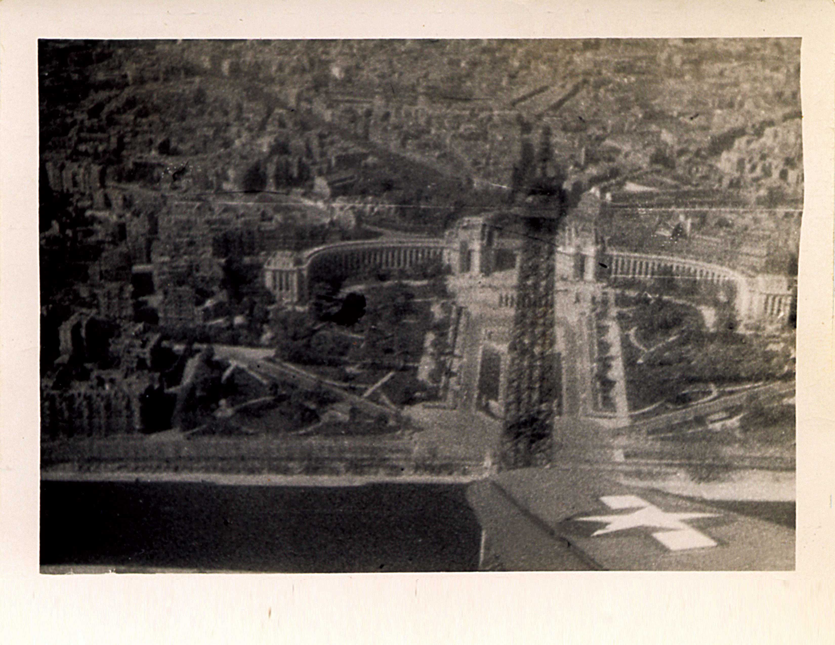 A black and white photo shows the city of France from a high altitude; the image has a hazy quality. The Eiffel Tower is visible.