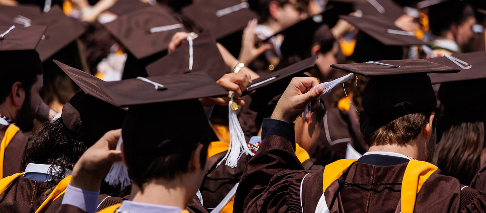 Students at the 2024 Commencement move the tassels on their caps.