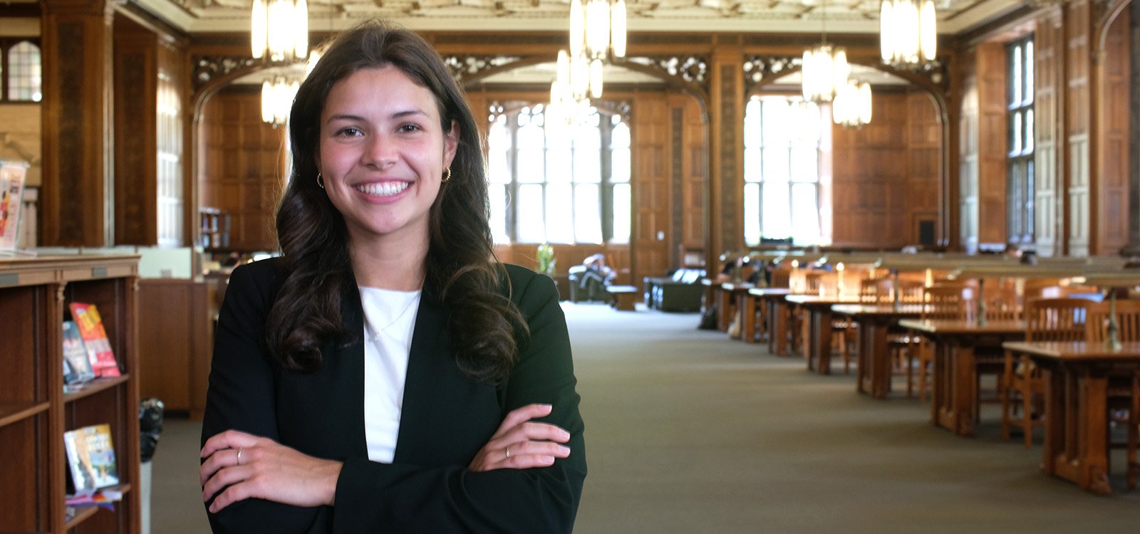 Delfina Szigethy crosses her arms in a suit inside Linderman Library