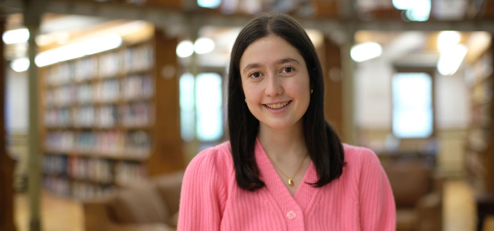 Abby Fischler wears a pink sweater inside Linderman Library.