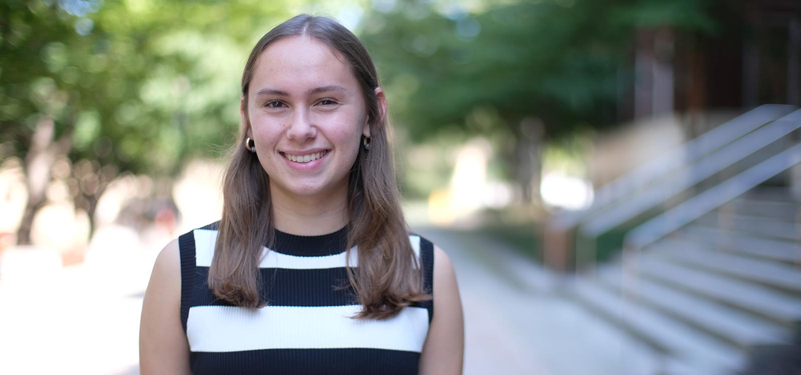 Charlotte Witmer-Rich wears a striped shirt and stands near Williams Hall.