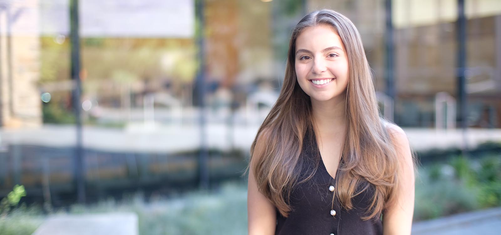 Stephanie Percello wears a black shirt and stands near the Business Innovation Building.