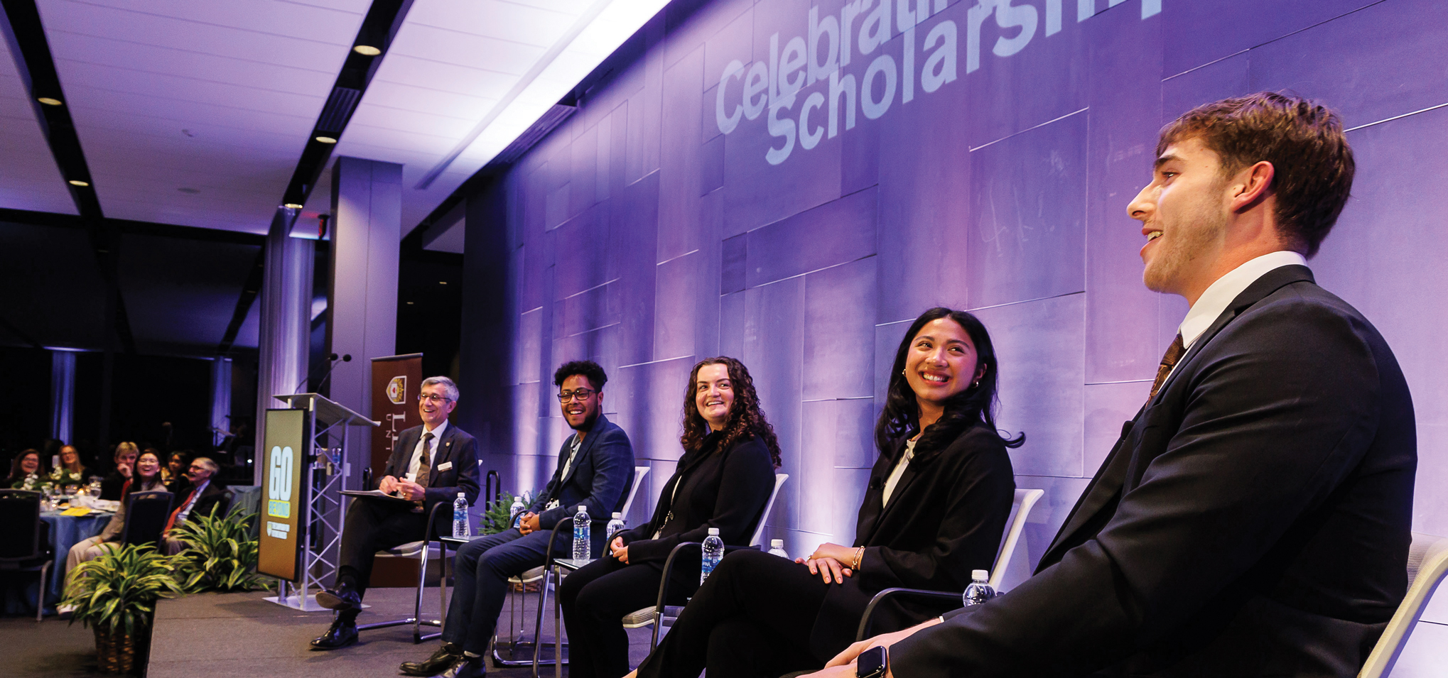 Scholarship recipients sitting on stage with President Helble