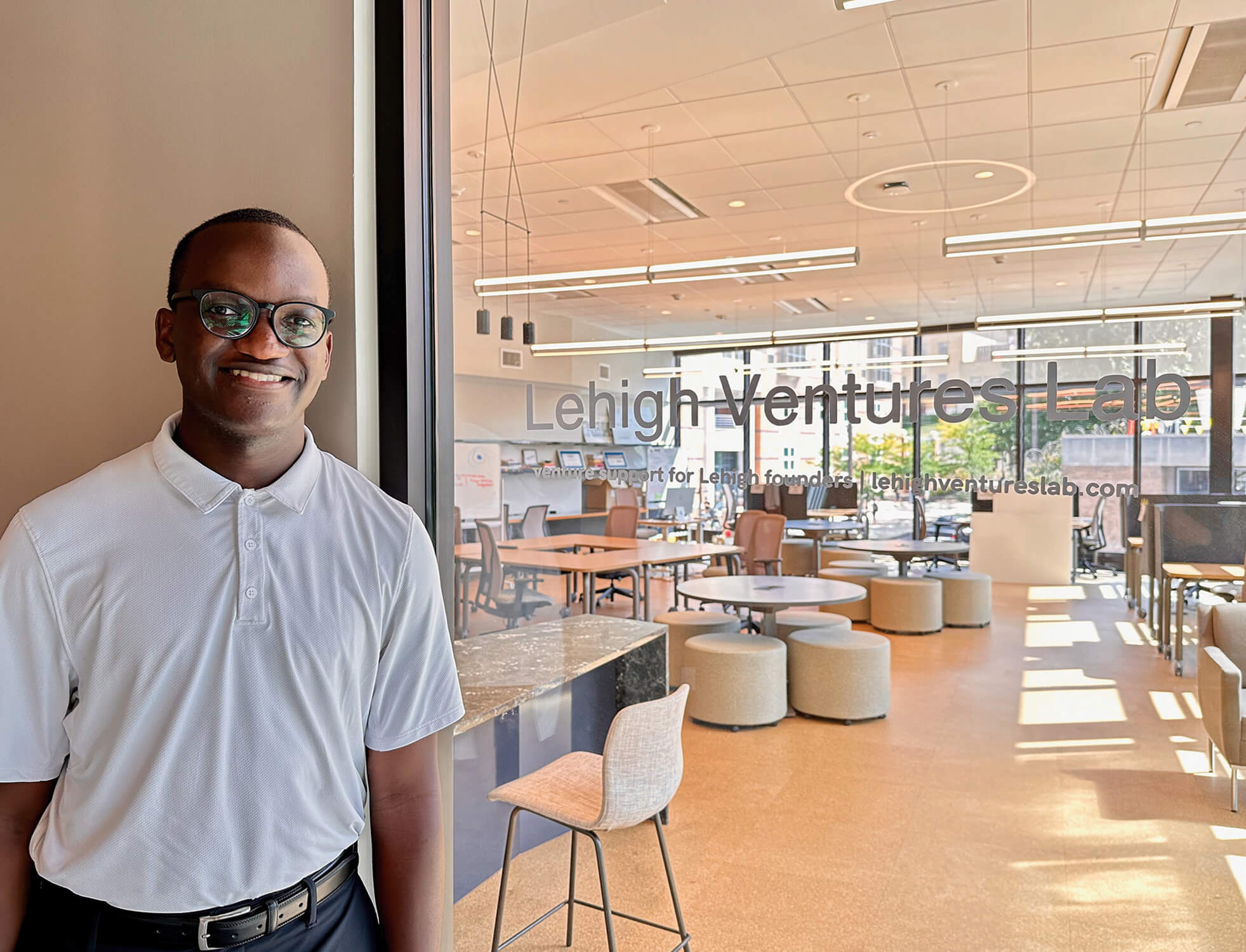 A student stands outside a glass door that reads “Lehigh Ventures Lab”, with collaborative work spaces shown inside.