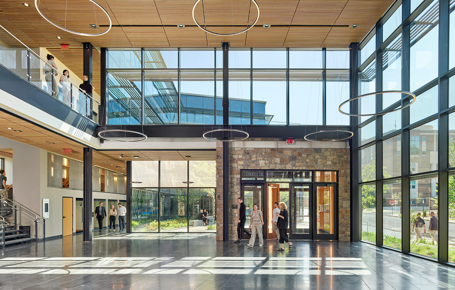 A view of the interior of the Business Innovation Building shows people entering lobby adorned with high ceilings and floor-to-ceiling windows.