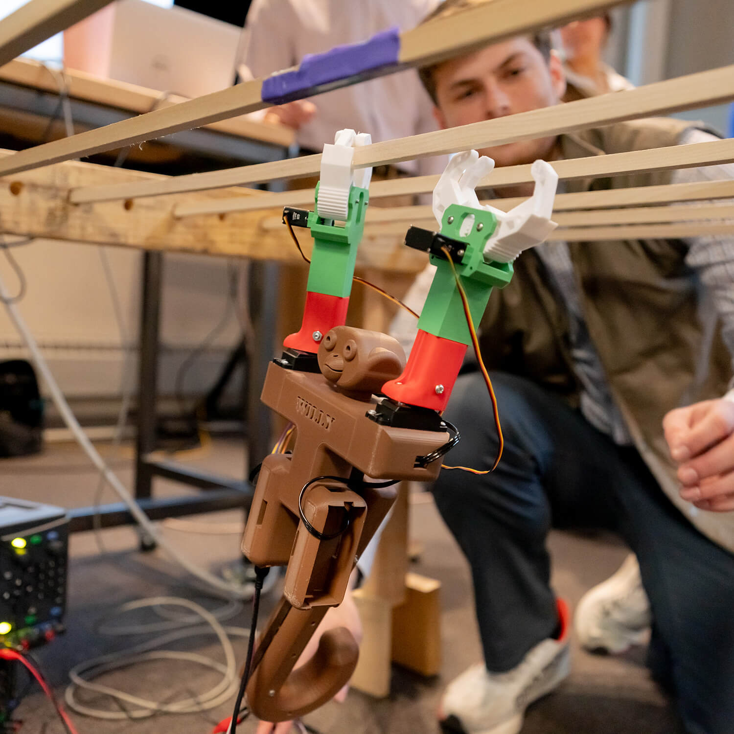  A student watches from behind as he tests a monkey-like robot on wooden obstacles.