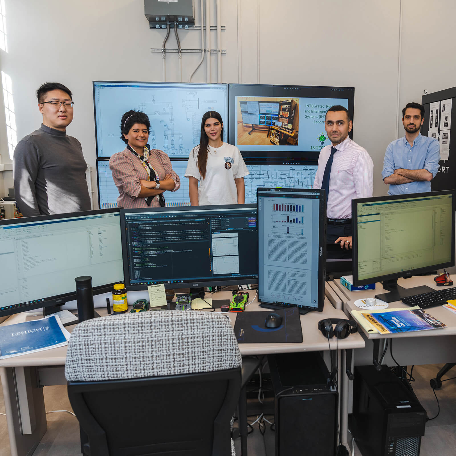 n a room filled with computers and monitors, students and professors pose together.