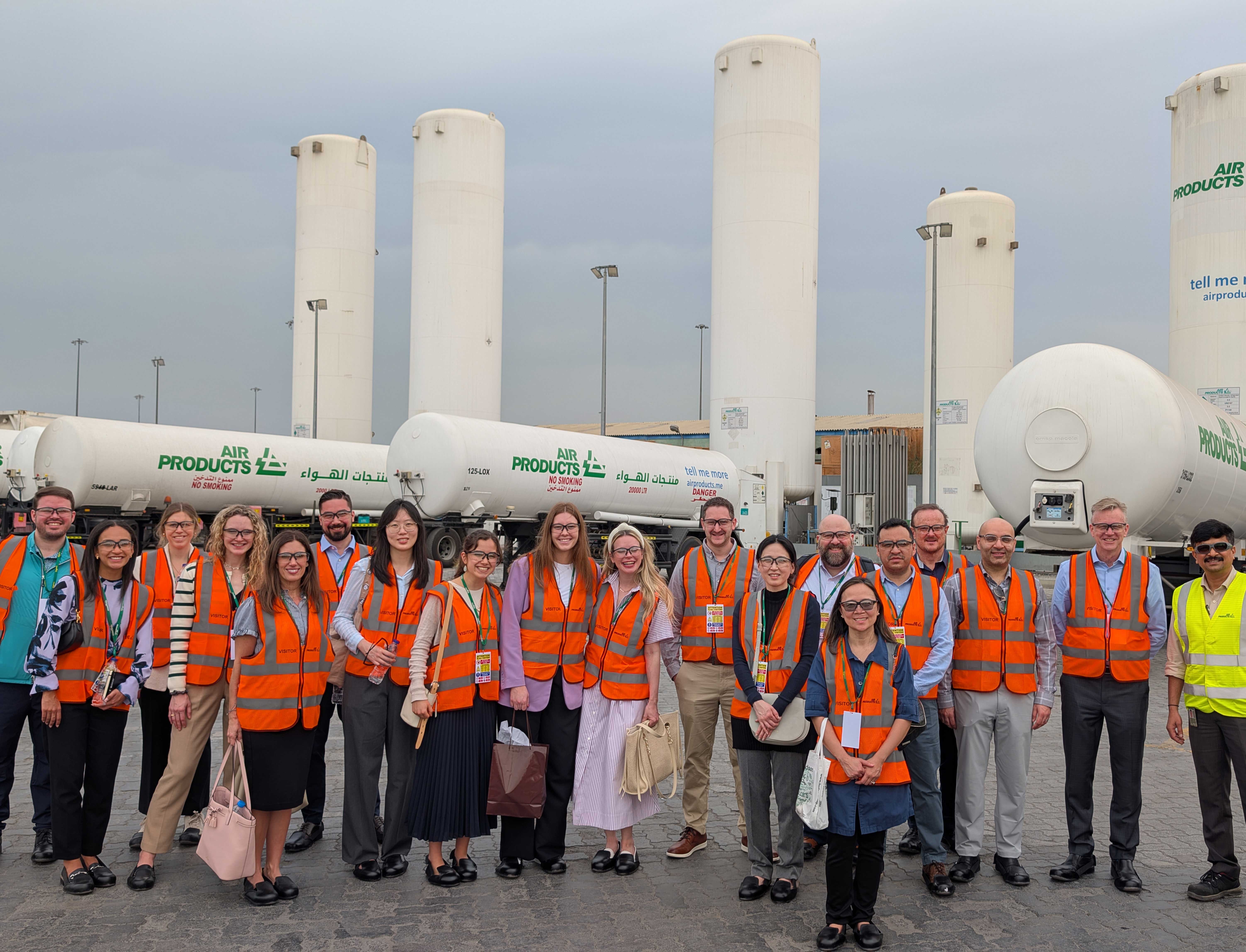 A group of FLEX MBA students pose together at the Air Products facility in Dubai. They each wear neon orange vests.