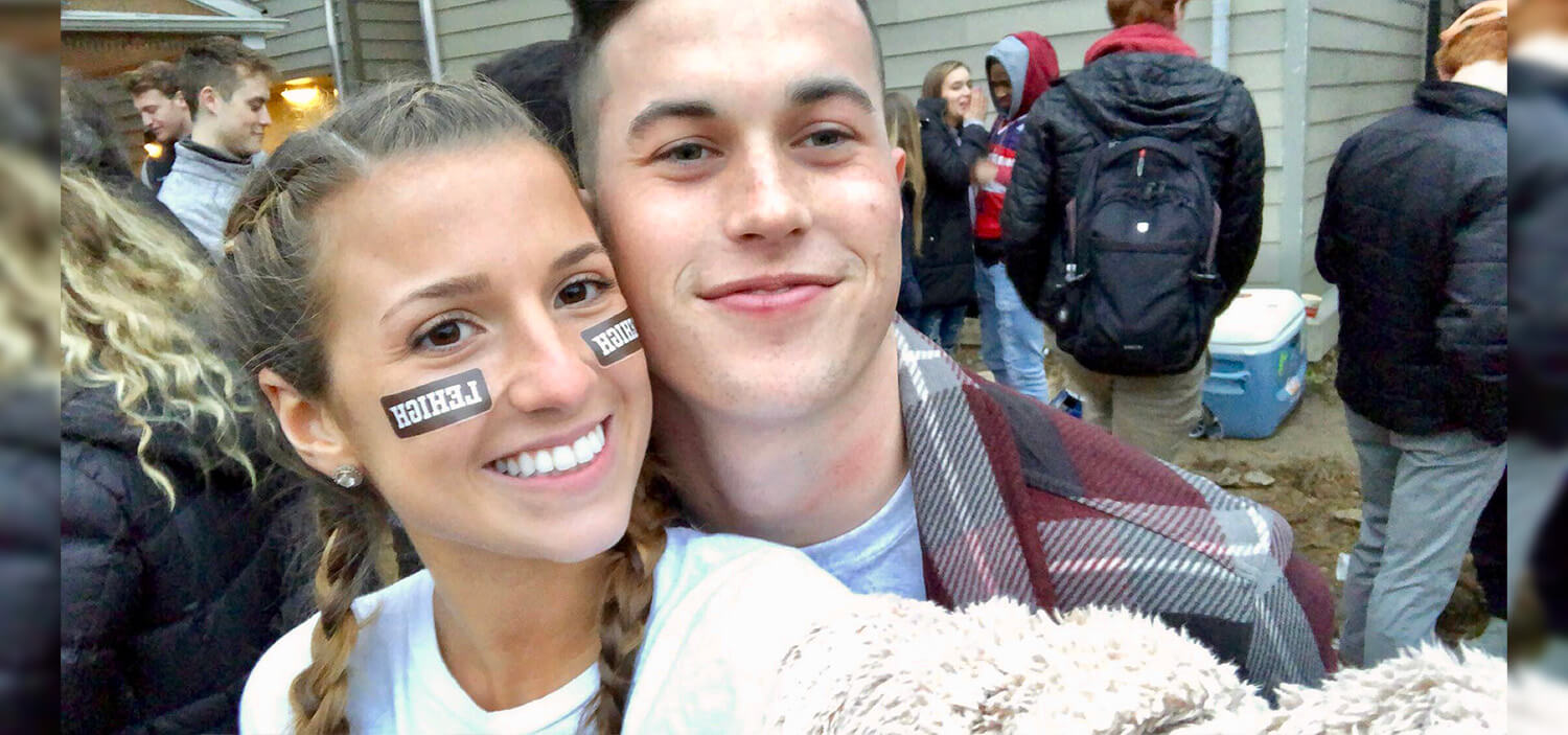 A couple poses, smiling, cheek to cheek, the girl has Lehigh stickers on her cheeks.