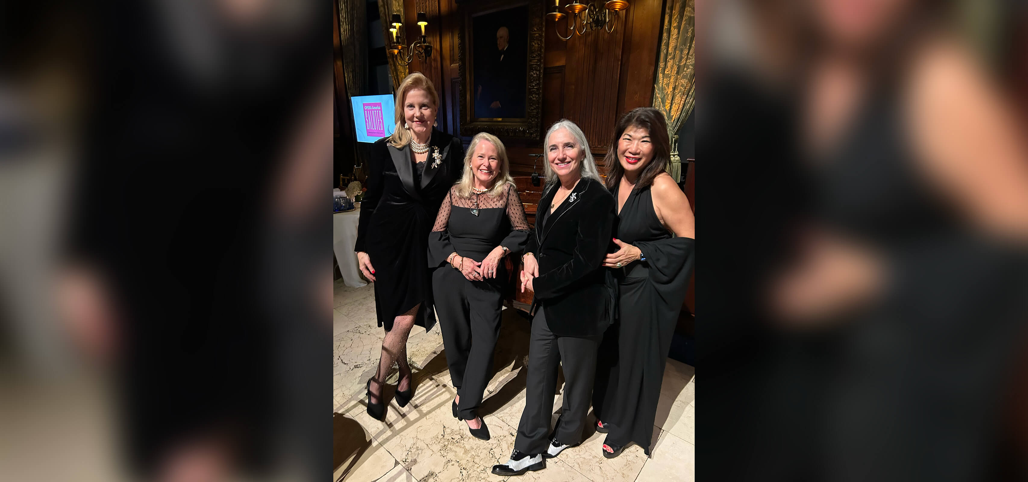 Four alumnae stand side-by-side, elegantly dressed at a formal event.