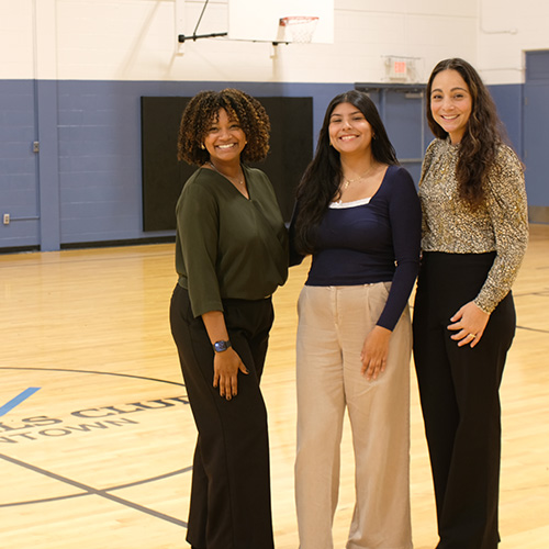 Three women stand together in a gym
