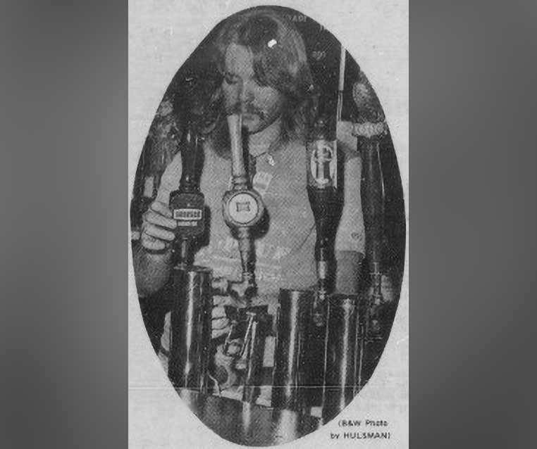 A male student with long hair pulls down the handle of a beer tap into his waiting glass.