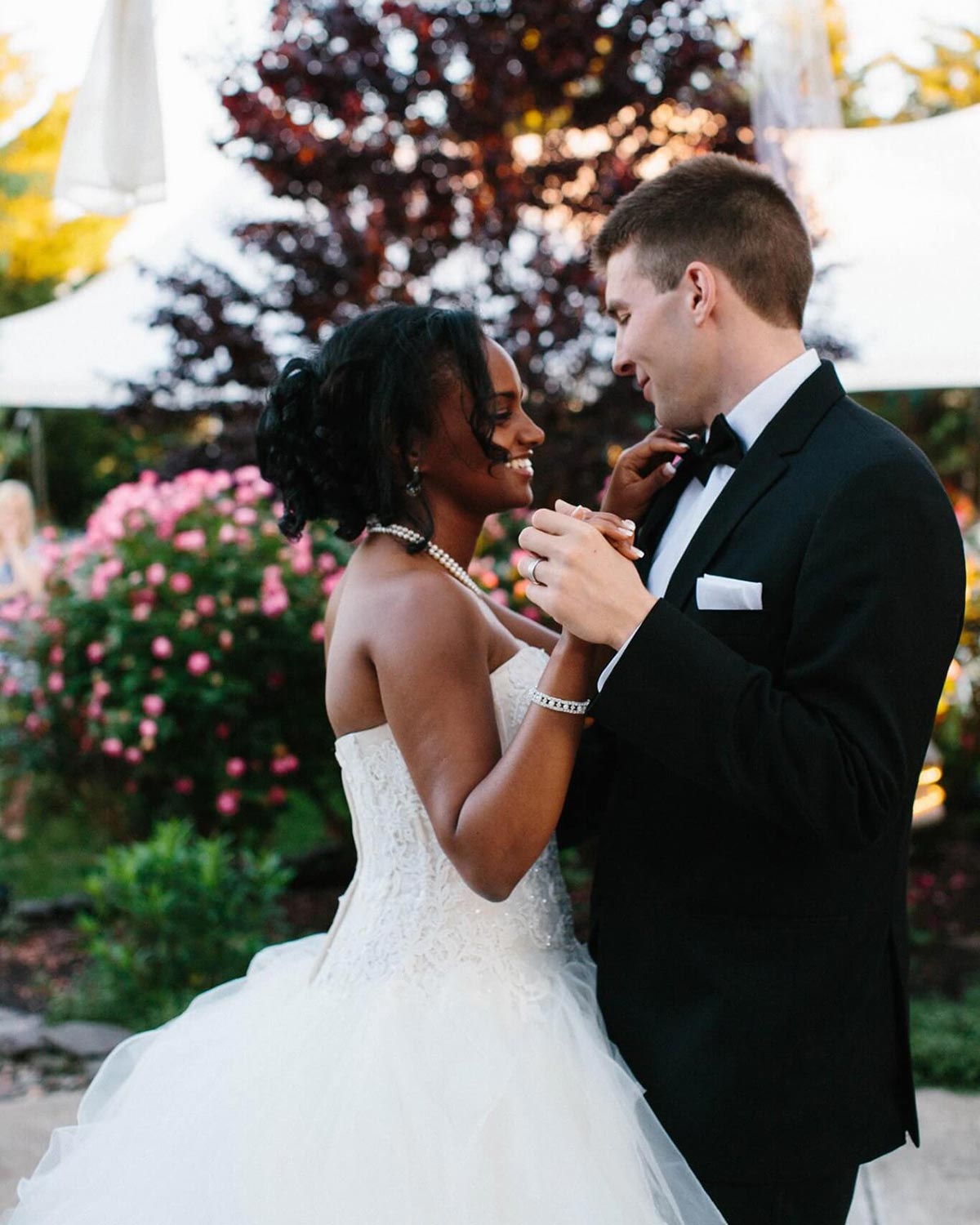 Betty and Tyler dance at their wedding with smiles on their faces; she wears a white wedding dress and he wears a black suit