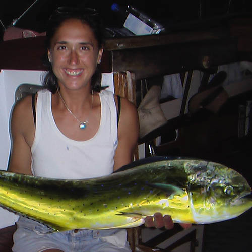 A woman in a tank top holds a long bright green fish