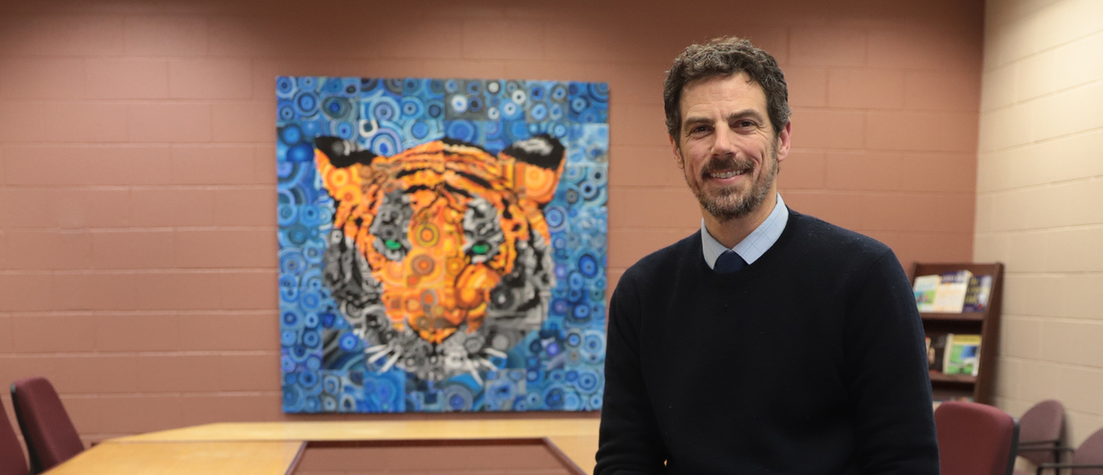 Adam sits in front of a tiger painting