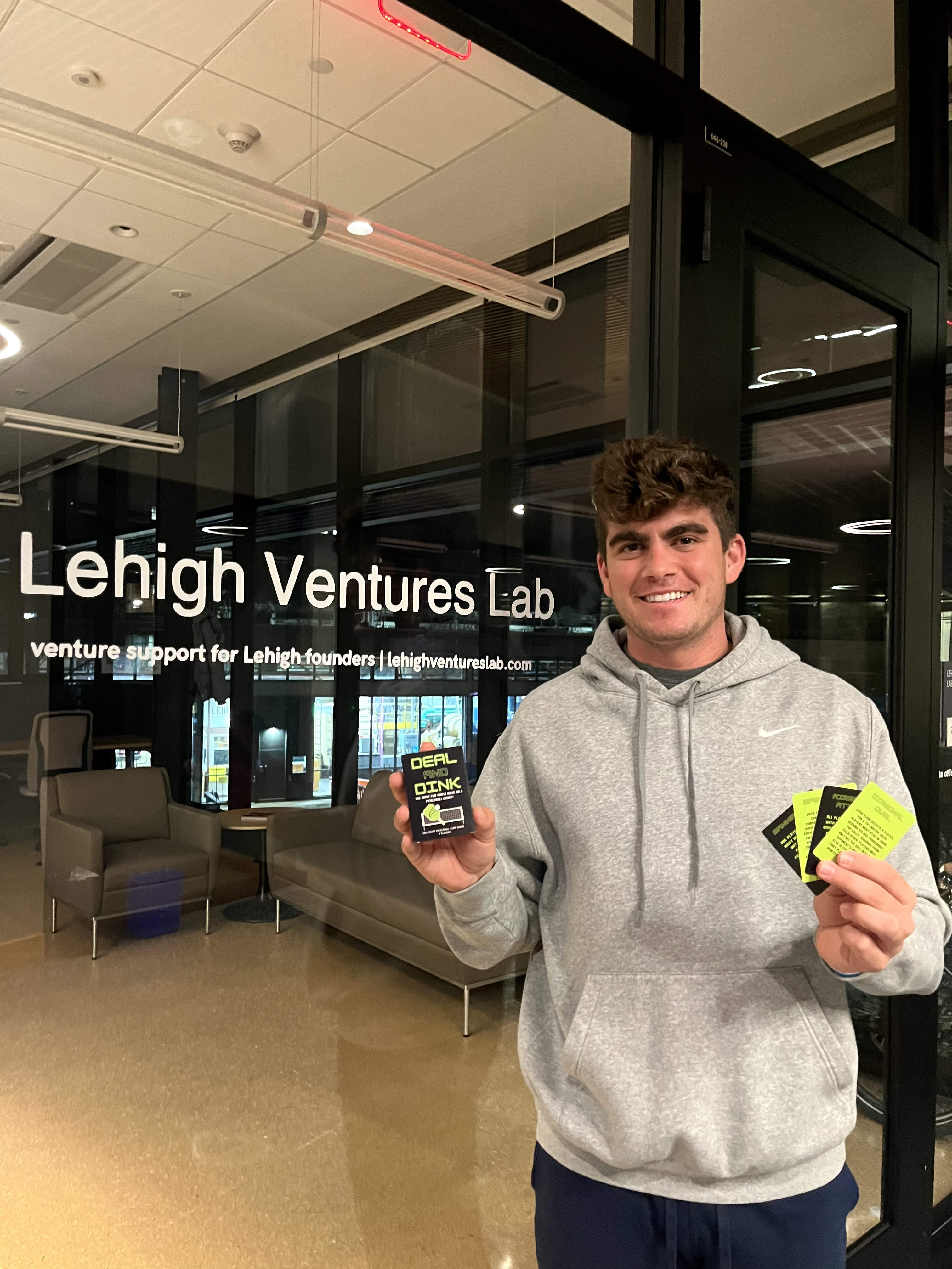 Canaan Kimball poses with playing cards from his Deal and Dink game in front of the Lehigh Ventures Lab.