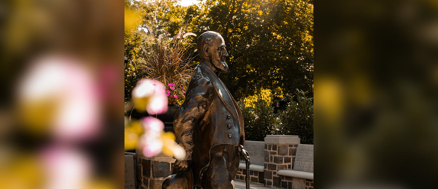 A profile view of an Asa Packer statue featuring flowers and sun glares.