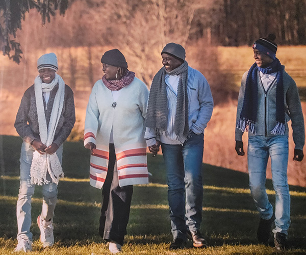 Christine Marty-Ochola walks outside with her husband and sons. All wear knit beanies and scarves.