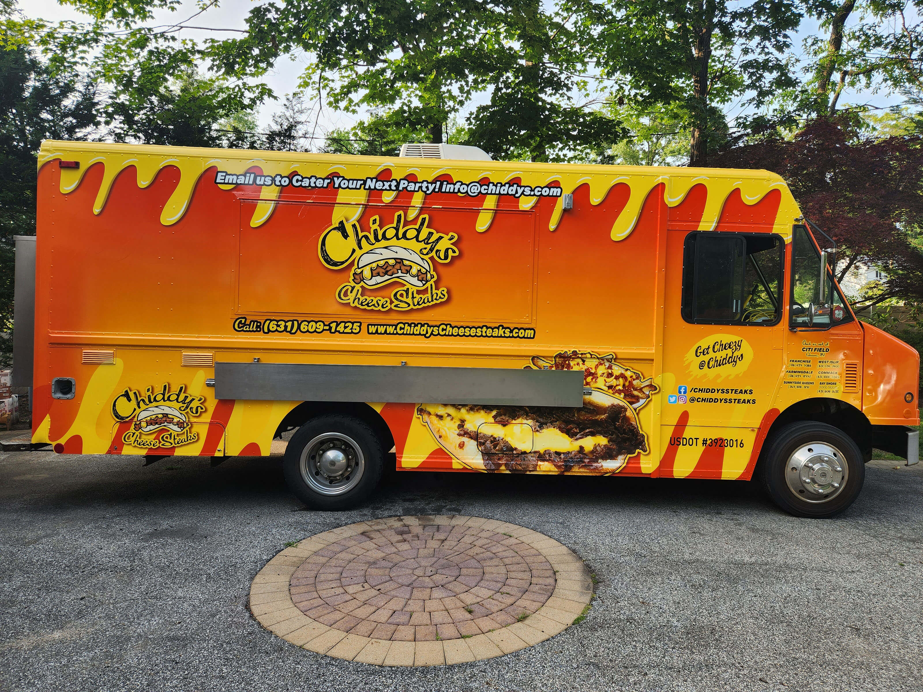 A large, brightly colored food truck with the Chiddy's Cheesesteak logo and yellow cheese-inspired graphics dripping on the top