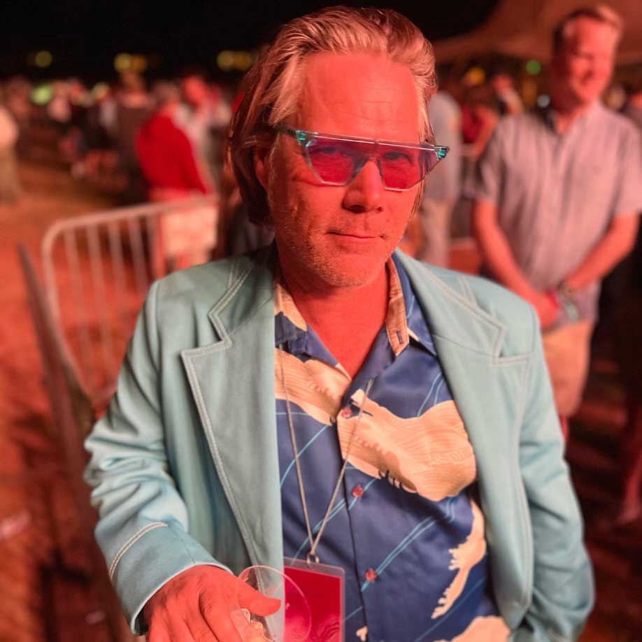 Chris at Fort Desolation Fest in Utah. It's evening, and he wears a bright blue blazer along with glasses.