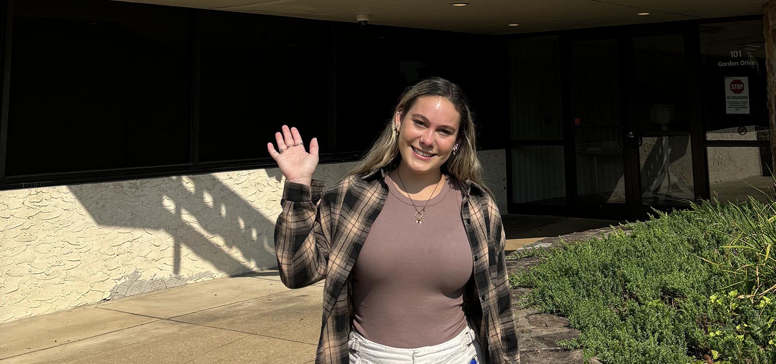 Dani Schmoyer waves hello at the entrance of the company